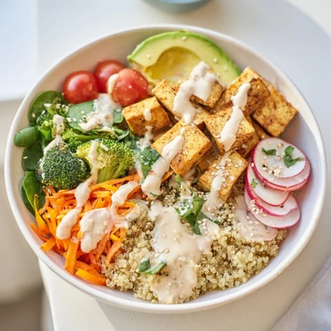This delicious Buddha bowl features tender tofu, fresh spinach, and creamy tahini dressing over grains.