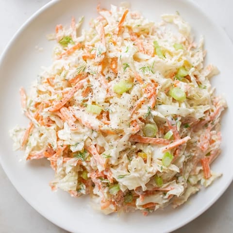 A colorful bowl of Coleslaw with Apple, featuring crisp cabbage and sweet, grated apple pieces.