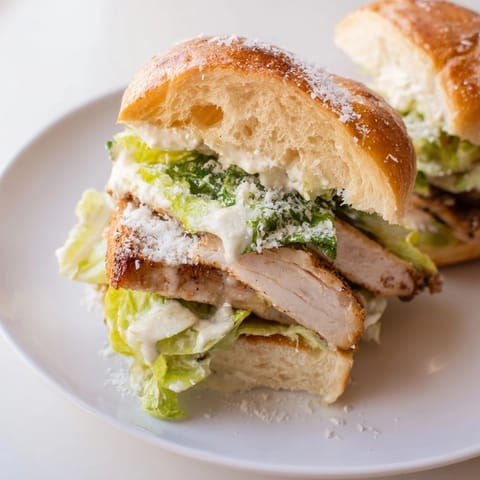 Caesar Chicken Sandwich on a plate with melted Parmesan and a drizzle of dressing.