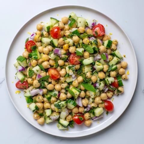 A close-up of vibrant Lemon Herb Chickpea Pasta Salad, highlighting fresh dill, mint, and zesty lemon dressing.  