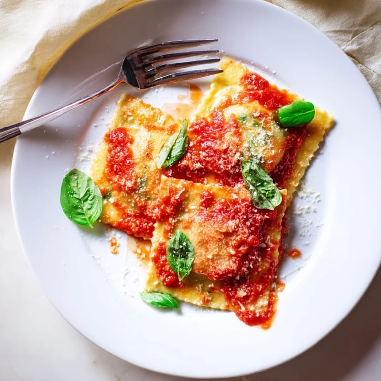 Spinach ricotta ravioli served in a rich red sauce, topped with extra Parmesan and ready for a satisfying weeknight meal.