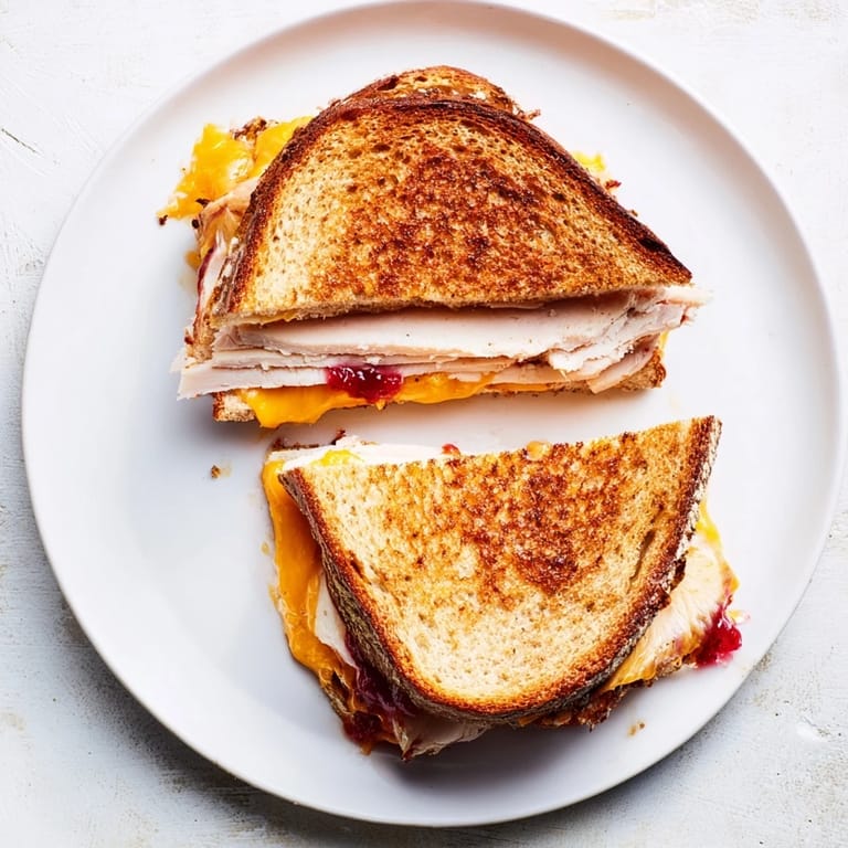 Hearty smoked turkey grilled cheese on sourdough, featuring a zesty cranberry spread and melted cheddar on golden toast.