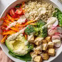 A colorful Buddha bowl overflowing with quinoa, tofu, and vibrant vegetables, ready to eat.