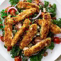 Crispy Chicken Kale Salad features golden-brown chicken cutlets on a bed of fresh kale, tossed with cherry tomatoes and a tangy maple-Dijon dressing.