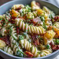 Hawaiian Pasta Salad with Ham, Pineapple, and Ranch in a creamy dressing, topped with fresh herbs for a tropical potluck dish.  